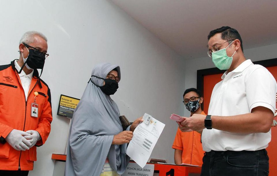 Menteri Sosial Juliari P Batubara (kanan) memberikan uang bantuan pemerintah kepada warga saat meninjau pencairan bantuan sosial tunai (BST) di Curug, Tangerang, Banten, Sabtu (25/4/2020). © Antara