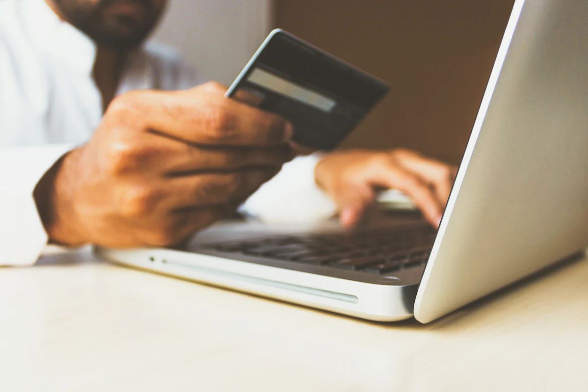 Seseorang memegang kartu di depan laptop. (Foto: Unsplash.com)