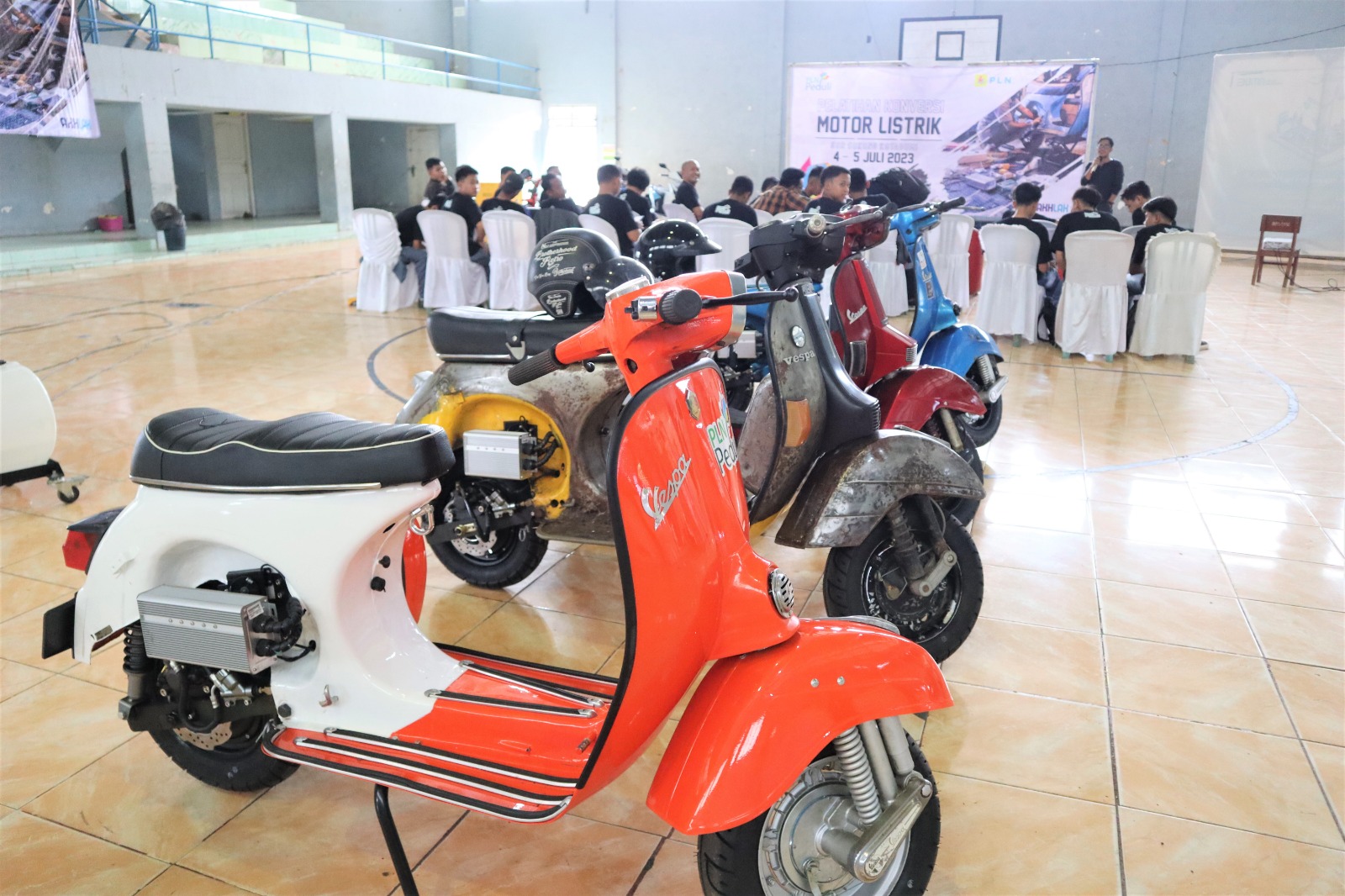 Tampilan motor berlatar suasana pelatihan konversi motor listrik yang selenggarakan oleh PLN di GOR Sukung Kotabumi, Lampung pada 4-5 Juli 2023. (Foto: Istimewa) 