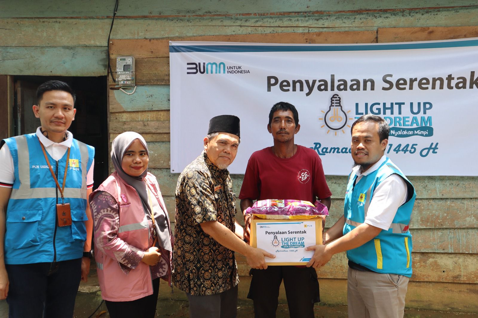 Penyalaan listrik penerima bantuan Light Up The Dream kepada Wagiran (kedua kanan) yang selama 3 tahun hidup dengan menyalur listrik dari tetangga beserta penyerahan bantuan sembako oleh Asisten 2 Kabupaten Bungo Saiful Azhar (tengah), dan Manager UP3 Muara Bungo Agung Pratomo (kanan). (Foto: Istimewa) 