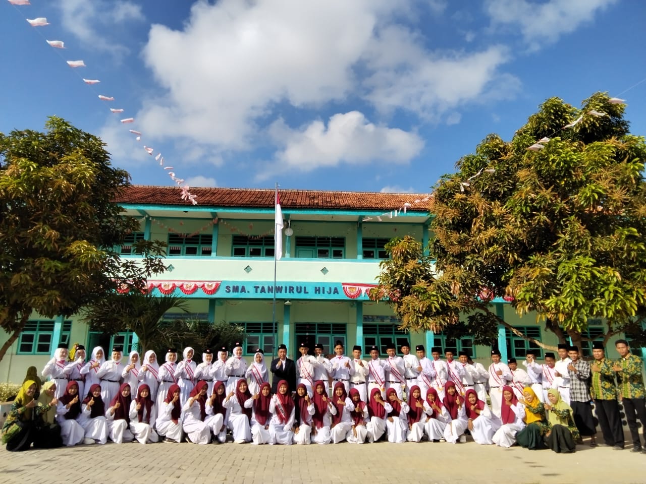Foto bersama petugas upacara dan Ketua Yayasan Tanwirul Hija di halaman sekolah setempat.