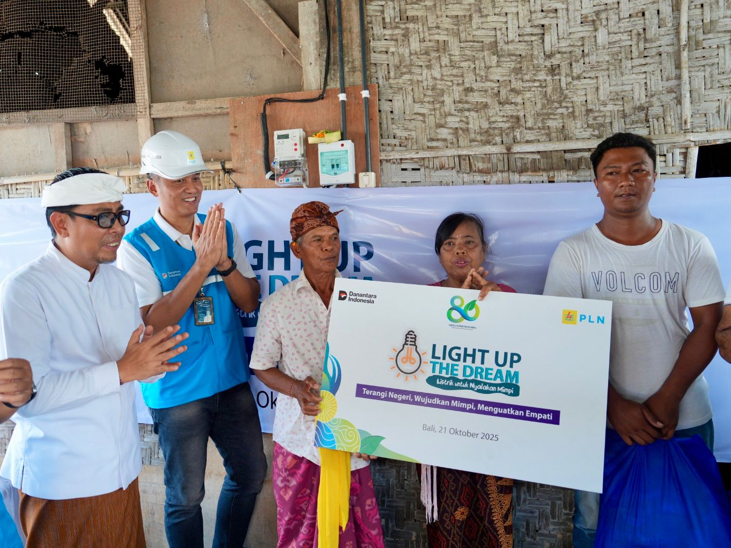Senyum bahagia terpancar dari I Nyoman Nuki (tengah) dan Made Rasmi (kedua dari kanan), pasangan suami istri penerima manfaat bantuan penyambungan listrik gratis PLN. Penyerahan simbolis dilakukan oleh GM PLN UID Bali Eric Rossi Priyo Nugroho (kedua kiri) dan Wakil Walikota Denpasar, I Kadek Agus Arya Wibawa (kiri) di Denpasar, Senin (21/10). (Foto: PLN) 
